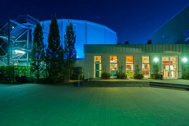 Rietberg_cultura_Günter Rolf_kulturig e.V..jpg Ein beleuchtetes Gebäude bei Nacht mit blauer Kuppel im Hintergrund und Eingangsbereich im Vordergrund.
