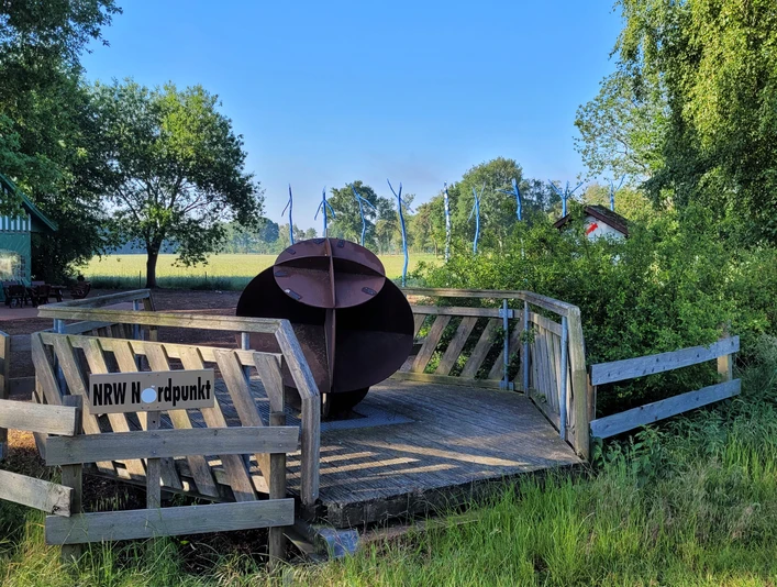 NRW Nordpunkt Holzplattform mit Geländer umschließt eine Skulptur in naturnaher Umgebung am nördlichsten Punkt NRW.