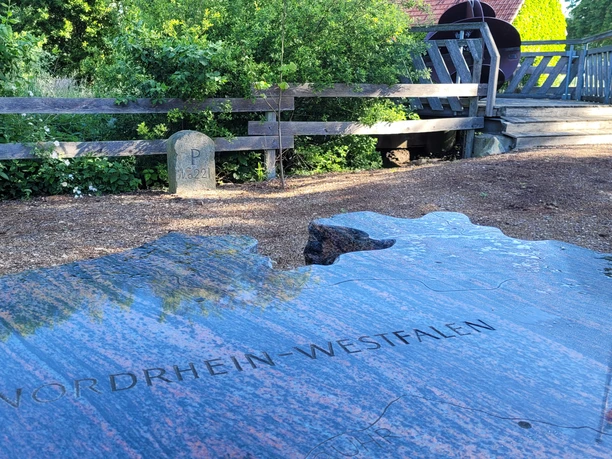 NRW Nordpunkt Gepflegter Standort am nördlichsten Punkt Nordrhein-Westfalens, umgeben von Holzgeländer und Grün.