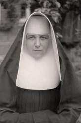 portraet_kunigunde_bearbeitet.jpg Porträt einer Ordensschwester in traditioneller Tracht mit ernstem Blick vor unscharfem Hintergrund