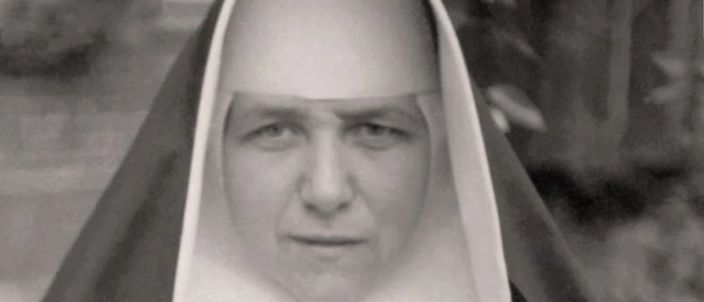 portraet_kunigunde_bearbeitet.jpg Porträt einer Ordensschwester in traditioneller Tracht mit ernstem Blick vor unscharfem Hintergrund