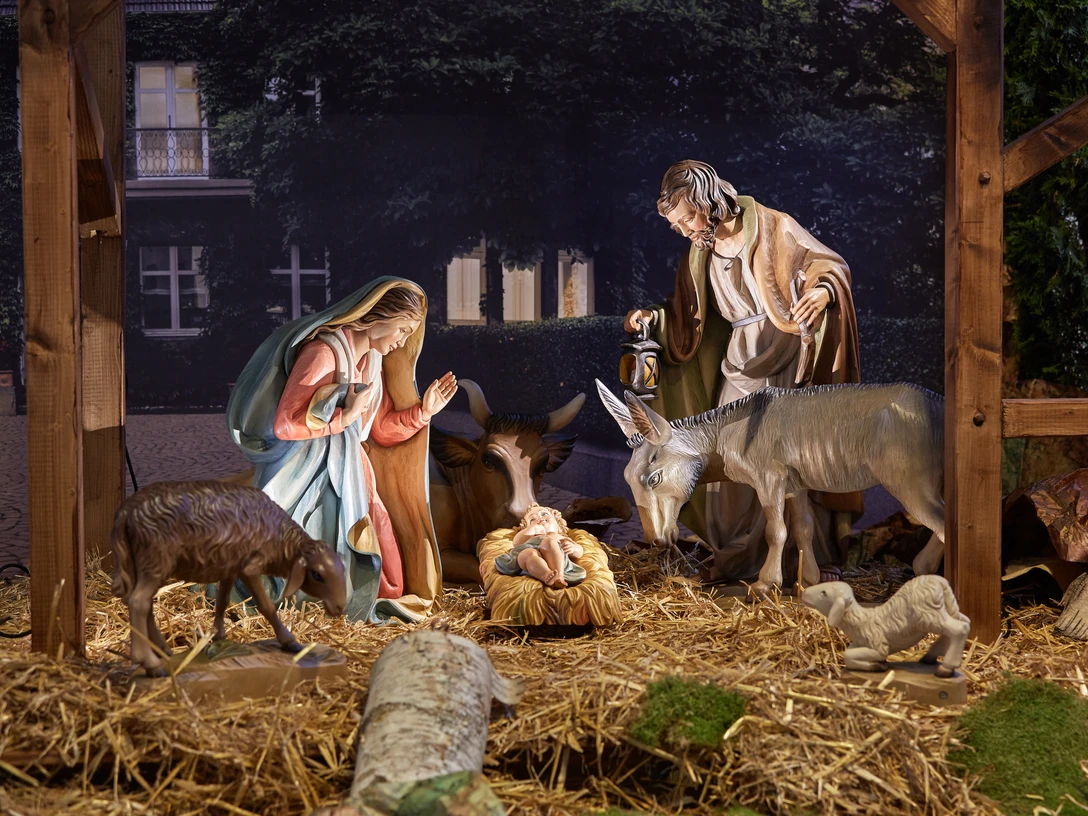 Nativity scene Krippenszene mit Figuren von Maria, Josef, Jesuskind, einem Esel und Ochse auf Stroh unter einem Holzstall.Nativity scene with figures of Mary, Joseph, baby Jesus, a donkey and ox on straw under a wooden stable.