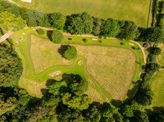 Luftaufnahme des Kurparks Bad Holzhausen mit grünen Wiesen, Wegen und dichten Baumgruppen.