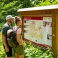 Zwei Wanderer lesen aufmerksam eine Informationstafel zu Wanderwegen im Wiehengebirge.