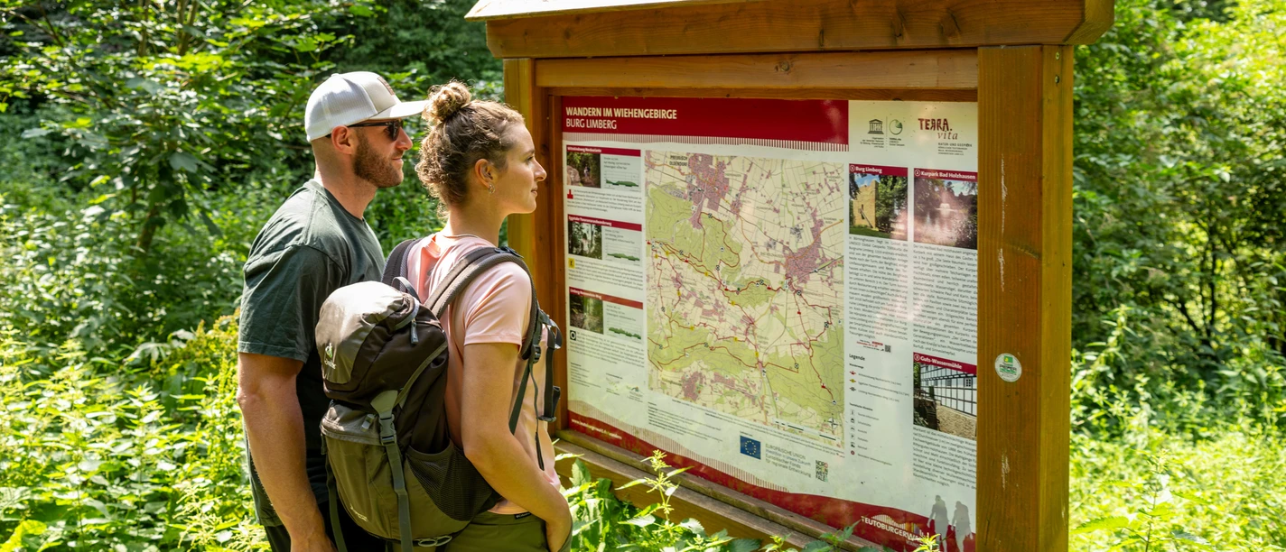 Preußisch-Oldendorf Wiehengebirge Zwei Wanderer lesen aufmerksam eine Informationstafel zu Wanderwegen im Wiehengebirge.