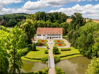Luftaufnahme des Kurparks Bad Holzhausen mit symmetrischen Blumenbeeten und einem historischen Gebäude.