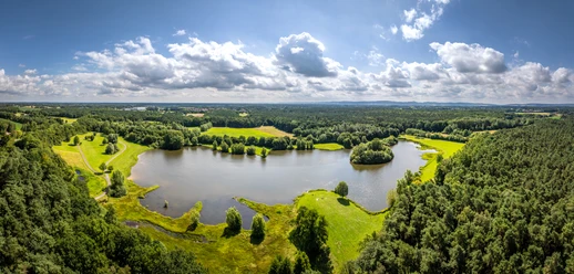 Espelkamp - See am Kleihügel Wunderschöner See mit bewaldeten Ufern, umgeben von grünen Wiesen und sanften Hügeln.