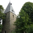 Kirche in Extertal-Almena.jpg Steinernen Kirchturm mit spitzem Dach in grüner Umgebung, historische Architektur in Extertal-Almena.