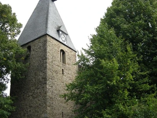Kirche in Extertal-Almena.jpg Steinernen Kirchturm mit spitzem Dach in grüner Umgebung, historische Architektur in Extertal-Almena.