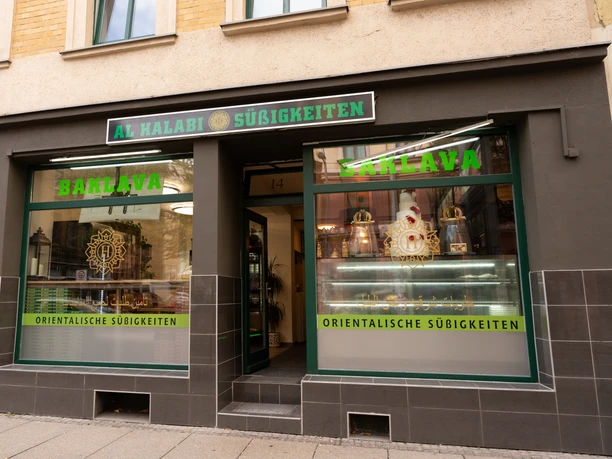 Al Halabi Außenansicht – Orientalische Süßigkeiten in Leipzig Das Schaufenster des Geschäfts Al Halabi ist in grün beschriftet mit "Baklava" und "Orientalische Süßigkeiten"