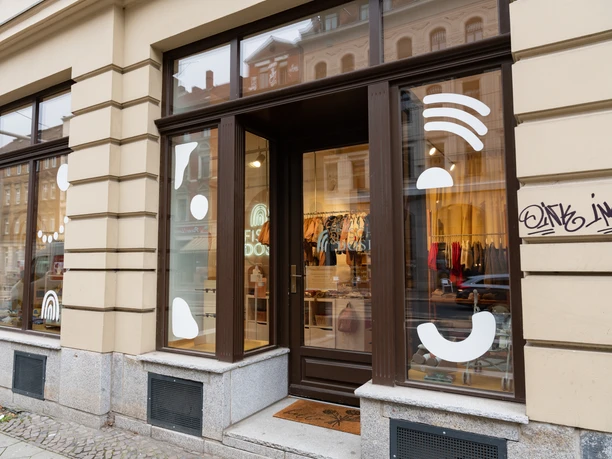 Fisch&Dose Schaufenster – Nachhaltige Kindermode in Leipzig Durch das schlichte Schaufenster des Kindermodegeschäft Fisch&Dose leuchtet die farbenfrohe Auswahl an Kindermode
