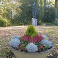 Friedenspark.jpg Ein herbstlicher Park mit einer dekorativen Pflanzschale im Vordergrund und einem Kunstwerk im Hintergrund.