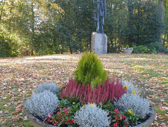 Friedenspark.jpg Ein herbstlicher Park mit einer dekorativen Pflanzschale im Vordergrund und einem Kunstwerk im Hintergrund.