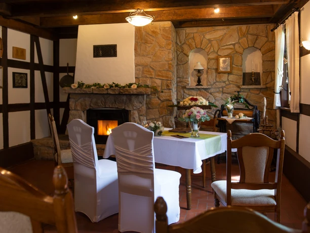 STANDESAMT VERSMOLD_0610_01.jpg Gemütlicher Raum mit Kamin, rustikaler Dekoration und gedecktem Tisch, ideal für intime Anlässe.