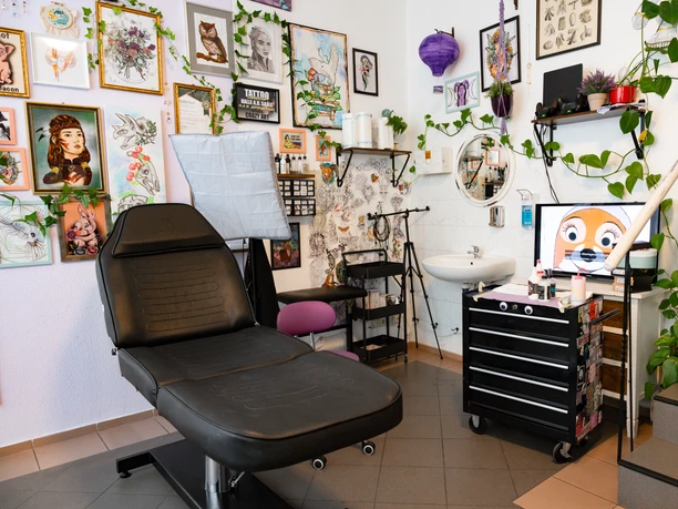 Many different pictures with sketches and designs hang on the wall of the tattoo studio