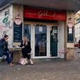Goldmund Vor dem Literaturcafé Goldmund sitzen zwei Menschen an einem Tisch, umgeben von urbaner Graffiti-Ästhetik.In front of the Literaturcafé Goldmund, two people are seated at a table, surrounded by an urban graffiti aesthetic.