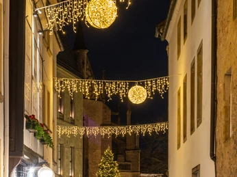 2022_12_MO_Weihnachtsbeleuchtung_@HolgerBulkPhotography-36.jpg Lichterketten und leuchtende Kugeln über einer festlichen, belebten Gasse mit Weihnachtsbaum.Fairy lights and glowing baubles above a festive, lively alley with a Christmas tree.Lyskæder og glødende kugler over en festlig, livlig gyde med et juletræ.Sprookjesverlichting en gloeiende kerstballen boven een feestelijke, levendige steeg met een kerstboom.
