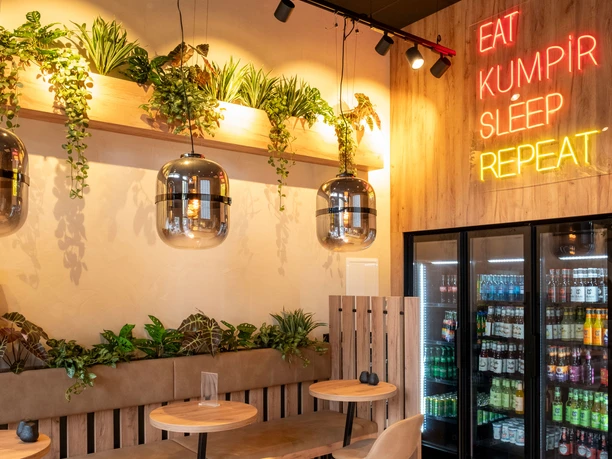 Restaurant Eat Kumpir Modern restaurant with wood-paneled walls and neon lighting.