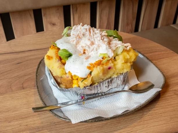 Restaurant Eat Kumpir Stuffed potato with spring onions, yogurt and cheese.