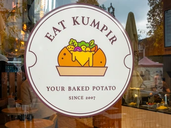 Restaurant Eat Kumpir Logo vom Restaurant platziert auf der Glasfront.Logo of the restaurant placed on the glass front.