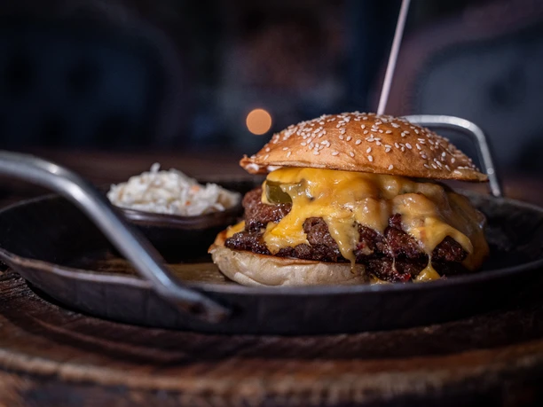 Ein schmackhafter Burger mit zerschmolzenem Käse und Patty in einer Eisenguss Pfanne.