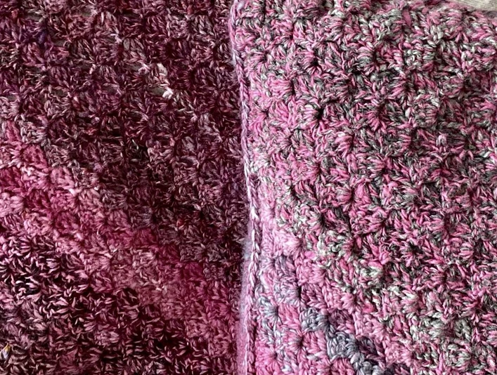 Gehäkeltes Stoffkissen Gehäkeltes Kissen und Decke in Rosa- und Lilatönen mit dichter, strukturierter Wolloberfläche