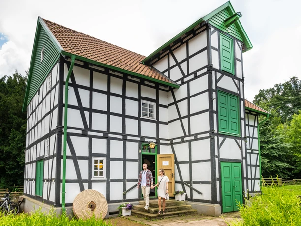 Gutwassermühle Hudenbeck Fachwerkhaus mit grünen Türen, historische Gutwassermühle Hudenbeck, Natur im Hintergrund.