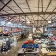 Eine beeindruckende Halle mit zahlreichen Oldtimern und Luxusfahrzeugen, umgeben von industriellem Charme.