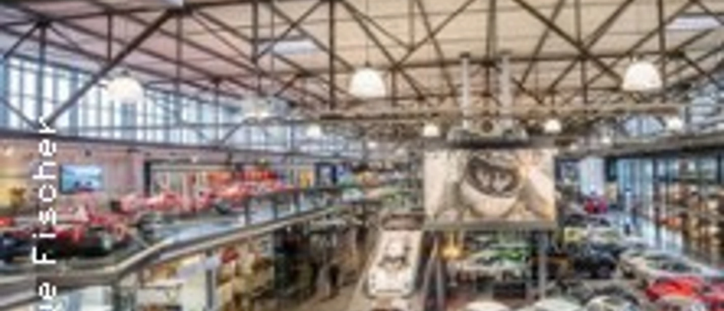 Eine beeindruckende Halle mit zahlreichen Oldtimern und Luxusfahrzeugen, umgeben von industriellem Charme.