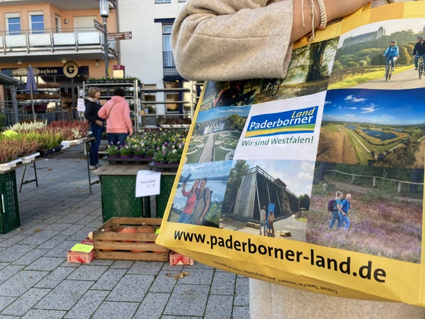 Büren Wochenmarkt Eine Einkaufstasche mit Paderborner Motiven wird auf einem belebten Wochenmarkt in Büren getragen.