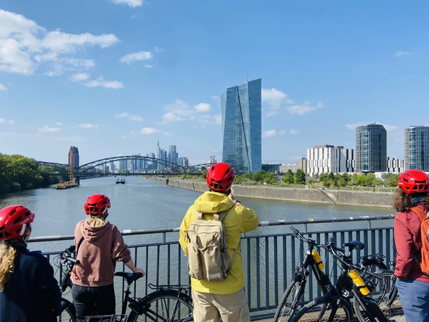 Cycling group on bridge with skyline by river
