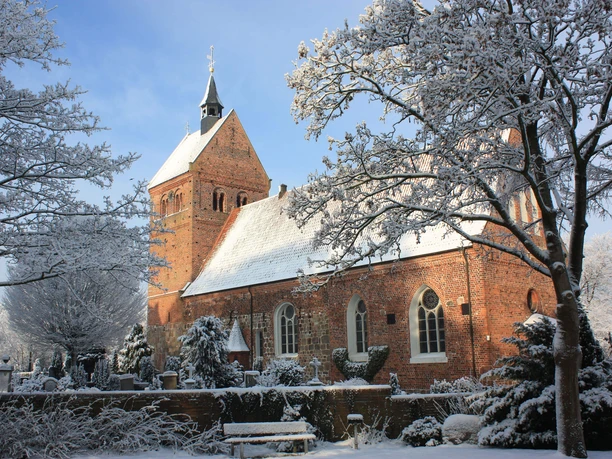 st.-johannes-kirche-im-winter.jpg St. Johannes-Kirche mit verschneitem Dach und Turm, umgeben von Bäumen und winterlicher Landschaft