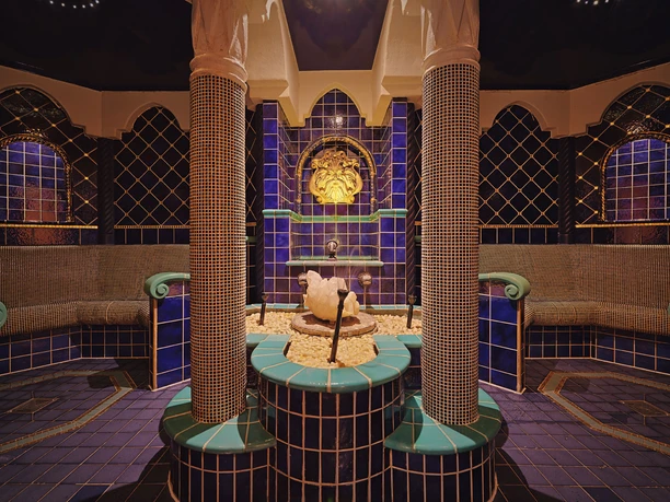 Saunalandschaft Wellnesspark Toskana Therme Luxuriöses Spa mit blauen und grünen Kacheln, zentralem Brunnen und kunstvollen Säulen, schafft eine entspannende Atmosphäre.
