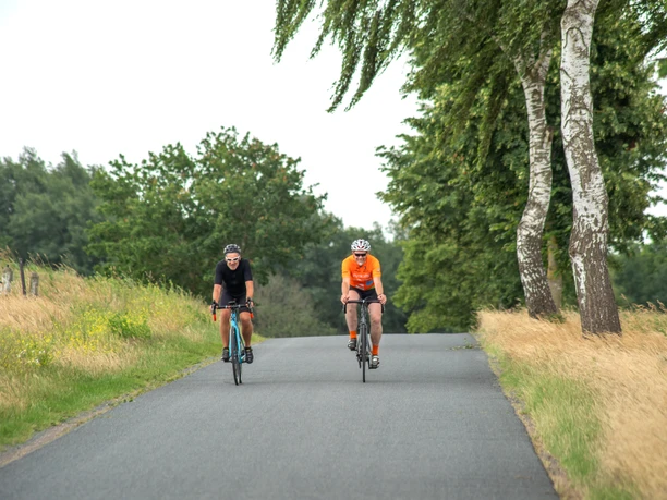 Zwei Rennradfahrer unterwegs auf einsamer Straße Zwei Rennradfahrer unterwegs auf einsamer Straße