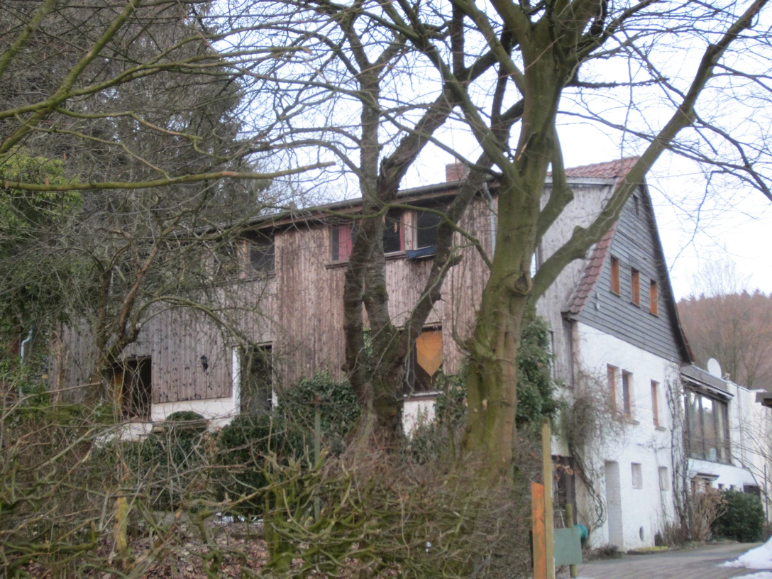 Bergheimat Oberbauerschaft Ein traditionelles Landhaus mit Holzelementen, umgeben von kahlen Bäumen an einem bewölkten Tag.