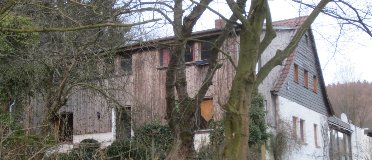 Bergheimat Oberbauerschaft Ein traditionelles Landhaus mit Holzelementen, umgeben von kahlen Bäumen an einem bewölkten Tag.
