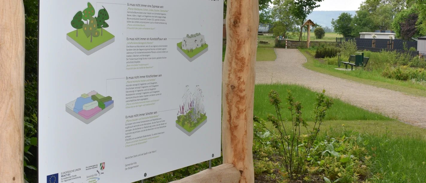 Reimlers Teich Informationsschild mit Text und Grafiken im Freien, umgeben von Naturwegen und üppigem Grün.