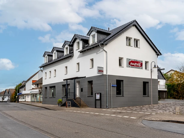 Modernes, zweistöckiges weißes Gebäude mit grauer Fassade und Anabel-Hinweisschild, ruhige Straße.