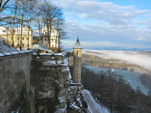 Festung Königstein Majestätische Festung Königstein im Winter, thront auf einem Felsen, von Schnee umhüllt.