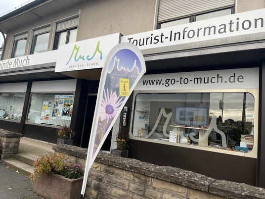 Tourist-Information Eingang der Tourist-Information Much mit Werbebanner und Schaufenstern voller Broschüren.