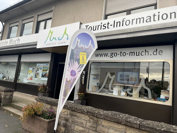 Tourist-Information Eingang der Tourist-Information Much mit Werbebanner und Schaufenstern voller Broschüren.