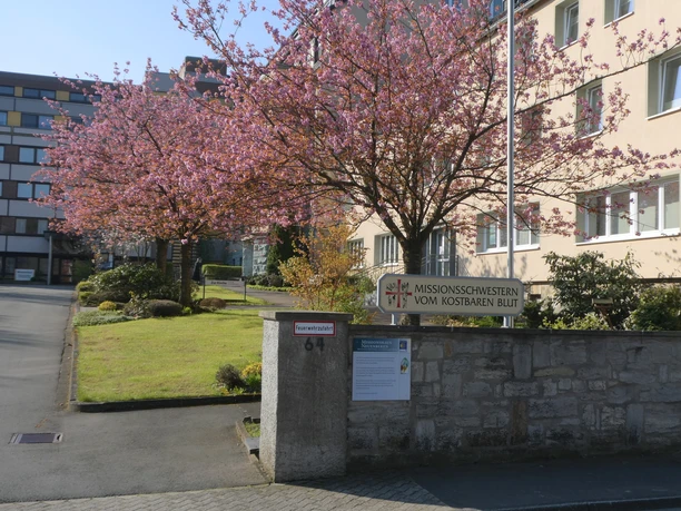 Missionshaus Neuenbeken Eingang des Missionshauses Neuenbeken mit blühenden Bäumen und angrenzender Rasenfläche im Frühling.