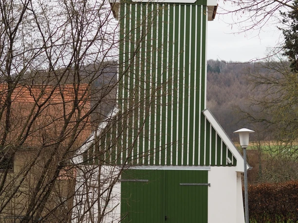 Altes Feuerwehrhaus_Schnathorst_Winter_01-24 (10).JPG Grünes, hohes Feuerwehrhaus mit rotem Ziegeldach und weißer Schrift, umgeben von kahlen Bäumen im Winter.