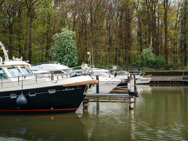 Mehrere Motorboote liegen an einem Steg im Yachthafen Lübbecke, umgeben von Bäumen.