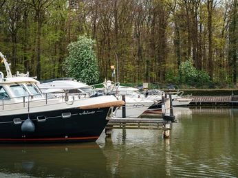 Yachthafen Lübbecke Mehrere Motorboote liegen an einem Steg im Yachthafen Lübbecke, umgeben von Bäumen.