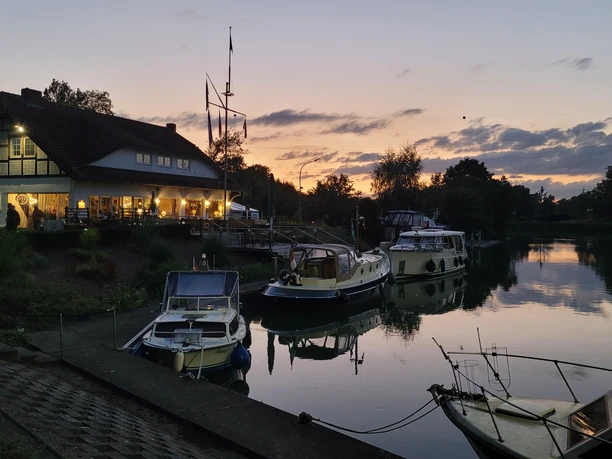 Yachthafen Lübbecke Bootsliegeplätze und ein Gasthaus reflektieren sich im ruhigen Wasser während der Dämmerung.