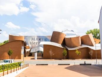 Museum Marta Herford mit seiner wellenförmigen Fassade aus Backstein und Stahl, bei sonnigem Wetter.