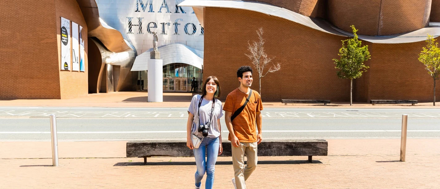 herford-marta-herford-teutoburger-wald-tourismus-h-tornow-012-jpg.jpg Außenansicht des Museums Marta Herford mit zwei lächelnden Menschen auf einem breiten Gehweg.