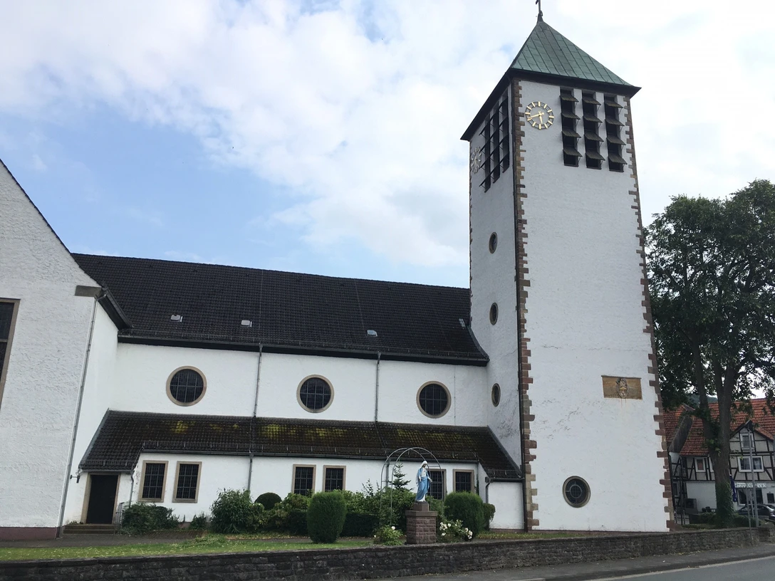 Katholische Wallfahrtskirche St. Marien Wallfahrtskirche St. Marien mit hohem Turm und Uhr, umgeben von Bäumen, nahe einer Straße gelegen.