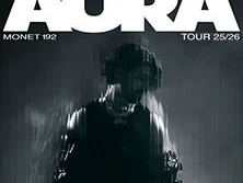 Monet192 vor schwarzem Hintergrund, umgeben von verwischten Lichtern, bewirbt die AURA Tour 25/26.